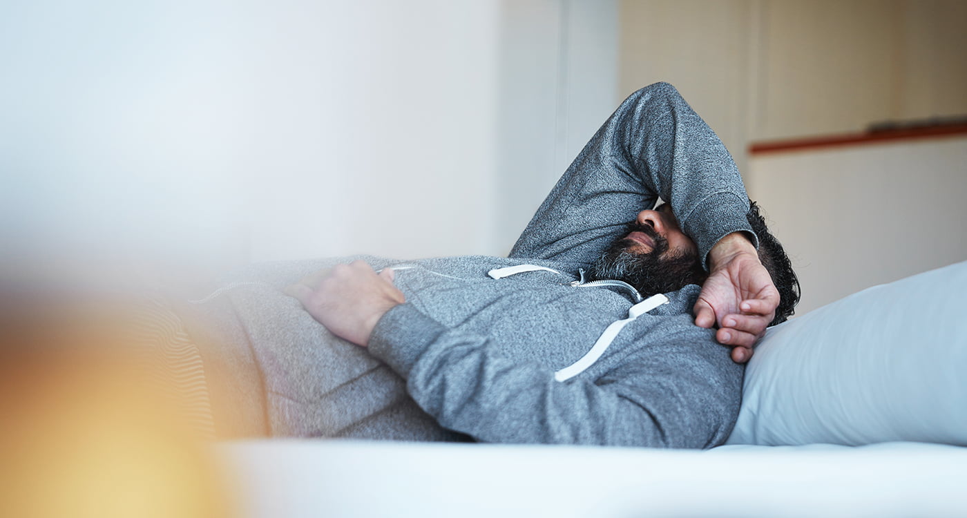 a man lying in bed with his arm over his face